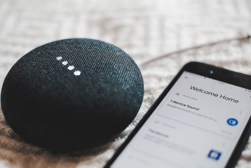 Google nest mini and a phone displaying the Google Home landing page